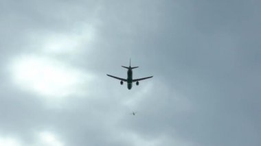 Bulutlu bir günde bir uçağın yavaş çekim silueti. Uçan ticari bir yolcu uçağı. Uluslararası havaalanından kalkan ya da inen bir jet uçağı.