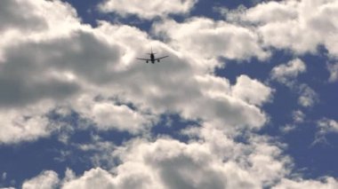 Güzel bir yaz gününde mavi gökyüzünde giysileriyle uçan bir uçağın yavaş çekim silueti. Ticari yolcu uçakları. Uluslararası havaalanından kalkan ya da inen bir jet uçağı.