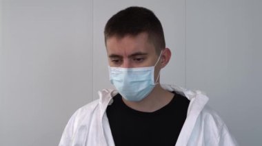Genç bir sağlık çalışanı kovid 19, koronavirüsü olan hastalara bakmak için hastanede koruyucu giysi giyiyor. Hemşire cerrahi maske ve eldiven takıyor..