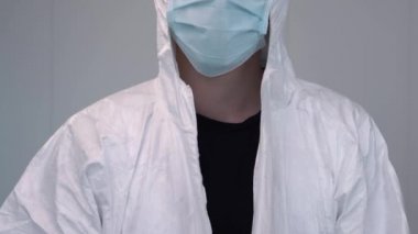 Bir hemşire koronavirüs salgını sırasında koruyucu giysi giyerek hazırlanır. Hemşire hastane ya da klinikte PPE kıyafeti, eldiven ve cerrahi maske takıyor..