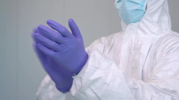 コロナウイルスのパンデミックの間の診療所のセットアップの内部で手を拍手し 手の手袋を身に着けている個人的な保護キットの医者の終わりのショット 病院の医療従事者 — ストック動画