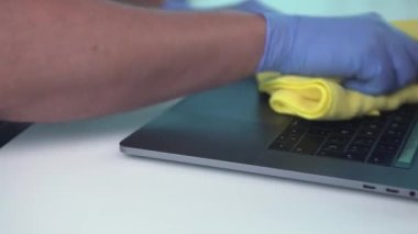 Coronavirüsü önlemek için dizüstü bilgisayarın klavyesini temizleyen ve dezenfekte eden biri. Çalışma alanını dezenfekte etmek için bez kullanılıyor..