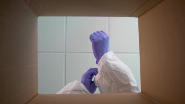 一位穿着防护服的男护士摘下手套扔进了垃圾堆 预防Covid 从垃圾桶里看 — 图库视频影像