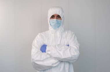 Koruyucu giysili bir sağlık çalışanı, kovid 19 Coronavirus salgını sırasında hastanede kollarını kavuşturuyor. Erkek hemşire cerrahi maske takıyor..