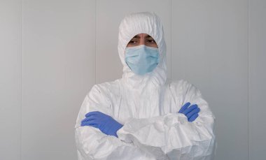 Koruyucu giysili bir sağlık çalışanı, kovid 19 Coronavirus salgını sırasında hastanede kollarını kavuşturuyor. Erkek hemşire cerrahi maske takıyor..