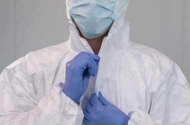 Bir hemşire koronavirüs salgını sırasında koruyucu giysi giyerek hazırlanır. Hemşire hastane ya da klinikte PPE kıyafeti, eldiven ve cerrahi maske takıyor..