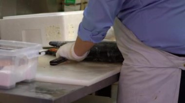 Tsukiji balık pazarında deniz ürünleri satan tüccarlar. Şef taze somon hazırlıyor, Japon bıçağıyla balık kesiyor restoranda bir kesme tahtasının üzerinde. Tokyo 'daki deniz ürünleri pazarı ve sağlıklı yiyecekler.