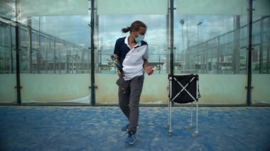 İspanya-31 Aralık 2020: Bir raket tenisçisi virüsü korumak için maske takıyor ve oynuyor. Kafkasyalı bir oyuncu topa vuruyor. Covid 19 salgınını ve sosyal mesafeyi önle - Dan