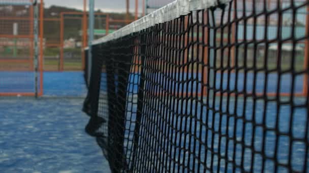 屋外の青いコートのネットにテニスボールを打つのスローモーション パドルをやっている人 近くに黄色のボールがネットに当たった スポーツコンセプト — ストック動画