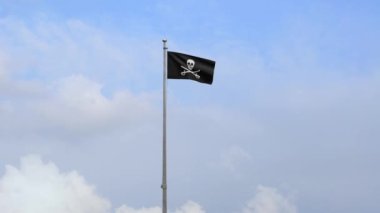 3D, korsan kafatasının kumaş dokusu ve mavi gökyüzünde rüzgarda dalgalanan kılıç bayrağı. Calico Jack korsan sembolü hacker ve hırsız konsepti. Dalgalı yüzey üzerinde siyah Korsanların gerçekçi bayrağı