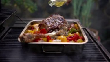 Şef barbeküde kuzu budu pişiriyor. Biber ve patates renginde metal tepside. Tatil tatillerinde BBQ of Garden Home 'da lezzetli keçi eti. İspanya 'da ızgara yemek.
