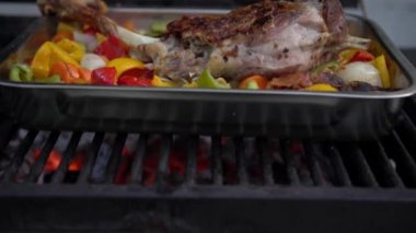 Şef barbeküde kuzu budu pişiriyor. Biber ve patates renginde metal tepside. Tatil tatillerinde BBQ of Garden Home 'da lezzetli keçi eti. İspanya 'da ızgara yemek.