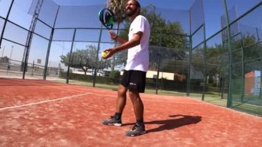 Seville, İspanya-21 Temmuz 2021: Açık hava sahasında görev yapan bir padel oyuncusunun hızlı hareketi. Servisten önce, topu birkaç kez sektirir..