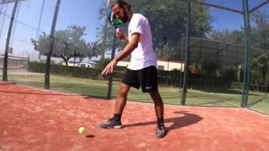 Seville, İspanya-21 Temmuz 2021: Açık hava sahasında görev yapan bir padel oyuncusunun hızlı hareketi. Servisten önce, topu birkaç kez sektirir..
