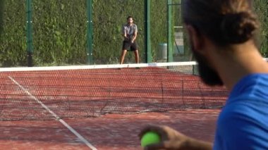 Seville, İspanya-03 Ağustos 2021: Açık bir sahada raket tenis oynayan iki kişi. Bir tanesi topa vurup kaleye doğru koşuyor..