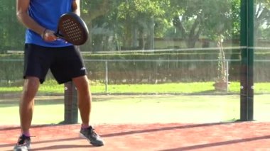 Seville, İspanya-03 Ağustos 2021: Profesyonel bir padel oyuncusunun açık hava maçında top almayı beklerken aktif kalması yavaş çekim.