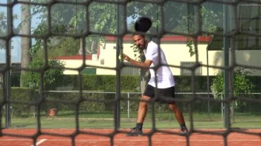 Seville, İspanya-21 Temmuz 2021: Profesyonel bir raket tenisçisinin açık hava sahasında servise ve internete doğru ağır çekimde koşması. Ağın arkasından bak.