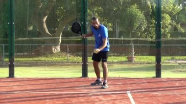 Seville, İspanya-28 Temmuz 2021: Bir raket tenisçisinin top sürmesi ve açık hava spor merkezinde servis etmesi.