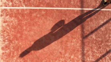 Dışarıdaki sahada raket oynayan birinin gölgesi görünüyor. Padel maçı veya turnuva.