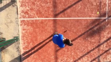 Açık hava sahasında maç yapan profesyonel bir raket tenisçisinin üst görüntüsü.