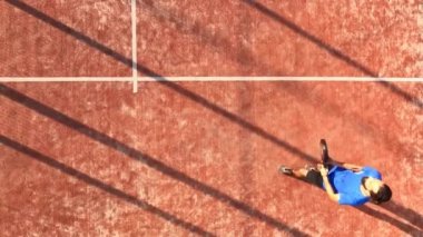 Açık bir sahada raket tenisi oynayan bir adamın yukarıdan çekimi. Padel yarışmasına hazırlanıyor..