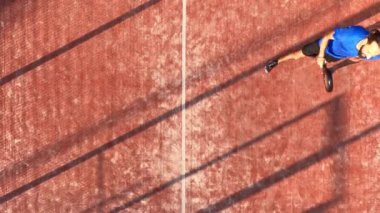 Açık hava sahasında maç yapan profesyonel bir raket tenisçisinin üst görüntüsü.