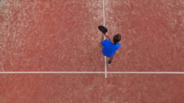 Açık hava sahasında raket oynayan genç bir adamın en iyi görüntüsü. Beyaz çizgilerin üzerinde yer alıyor..