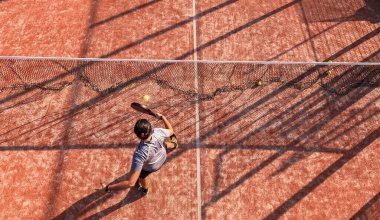 Profesyonel bir raket tenisçisinin açık hava sahasında topa vuruşunun en üst görüntüsü..