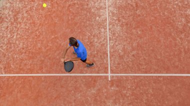 Açık hava maçında topa vuracak profesyonel bir raket tenisçisinin üst görüntüsü.