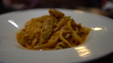 Restoranın masasında bir tabak spagetti bolonez. Lezzetli tipik İtalyan domates soslu makarna tarifi beyaz tabakta servis edilir. Geleneksel İtalyan mutfağı.