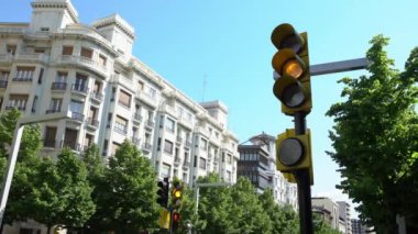 Zaragoza şehir merkezinin kesişen caddesinde yol ve ağaçların arka planında İspanyol bisiklet trafik ışıkları renk değiştiriyor. İspanya şehir merkezindeki kesişen yol kavşağında Semaphore ışıkları.