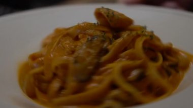 Restoranın masasında ağır ağır spagetti bolonez yiyorlar. Lezzetli tipik İtalyan domates soslu makarna tarifi beyaz tabakta servis edilir. Geleneksel İtalyan mutfağı.