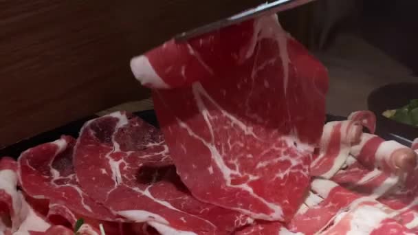 箸を使って中華鍋スープで肉を調理する ビュッフェレストランでは 新鮮でおいしい豚肉と牛肉の生のプレート 台湾の代表的な鍋ハーブ料理 — ストック動画