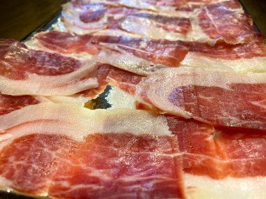 Jamon Serrano olarak da bilinen İspanyol kurutulmuş domuz dilimlerine yakın çekim. Tipik leziz tapa tabağı İber usulü jambon tabağı masada, İspanya 'nın geleneksel yemekleri.