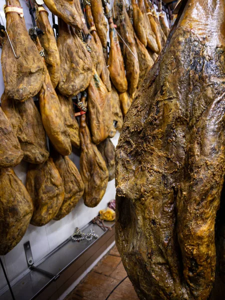 乾いた豚肉の太ももは 肉市場に掛けます 食料品店でハムやジャモンのスペイン料理 スペインのスーパーマーケットでイベリコ豚の買い物 乾燥して治癒したハムがぶら下がっている 市場は生肉製品を販売する — ストック写真