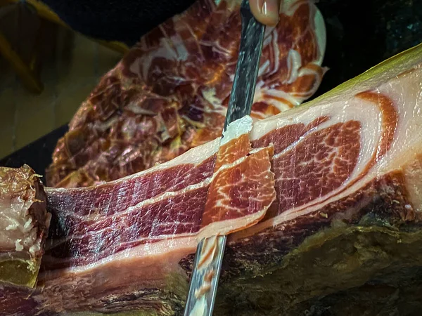 スペイン語でパタ ネグラとしても知られているセラノイベリアハムの前脚は 肉屋の切り身と木製のスタンドに取り付けられています — ストック写真
