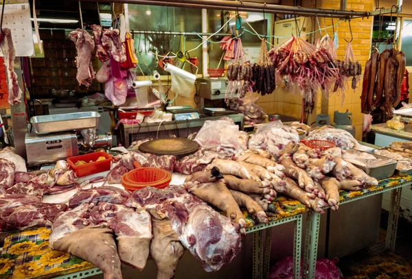 台湾のファーマーズマーケットの肉屋のカウンターで豚の新鮮な生の足 アジアのストリートフード市場で売られているポークナックルの購入者 — ストック写真