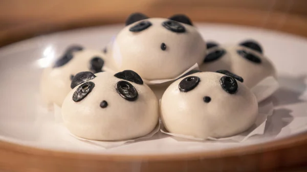 Chinese steamed buns in the shape of cute, adorable pandas in the wooden basket. The panda bread, also be called Baozi, served in dim sum at asian restaurant. Tasty and delicious china food dish
