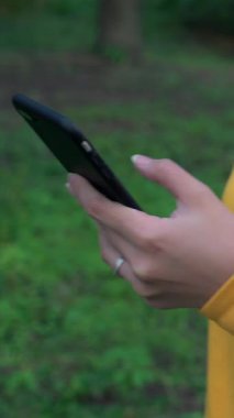  Asyalı bir kadın parkta yürür ve Taipei 'de akıllı telefon kullanır. Kız turist seyahati ve internette gezinmek için kullanılan telefon aygıtı, sosyal ağları kontrol etmek ve Tayvan bahçesinde metin yazmak için.