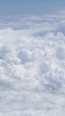 Gökyüzü açık mavi bulutlu harika bir manzara. Beyaz bulutların üzerinde bir uçağın penceresinden görülebilen güzel bir manzara. Uçaktan manzara.