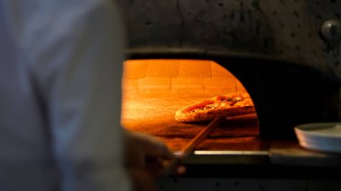 Bir pizza, odun ateşindeki bir fırının içinde bir taşın üzerinde durur, ve ateş ısısı onu mükemmelleştirir. Geleneksel yemek pişirme yöntemi bu İtalyan yemeğinin zengin lezzetlerini ortaya çıkarıyor..