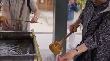 Japonya 'nın Fukuoka kentindeki Kushida Tapınağı' nın su havzasında geleneksel el temizleme ayini yapan bir kadının yavaş hareketi saygıyı ve ruhani temizliği simgeliyor.