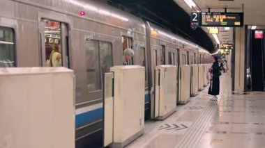 Fukuoka, Japonya-04 Ekim 2025: Aktif bir ulaşım ortamı, çeşitli insanlar, istikrarlı hareket ve modern ulaşım içinde ağır çekimli banliyö platformu boyunca hareket edenler