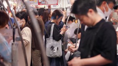 Fukuoka, Japonya-04 Ekim 2025: Yavaş çekim insanların Fukuoka, Japonya 'da kalabalık bir metro treninde birbirlerine yakın durduğunu gösteriyor.