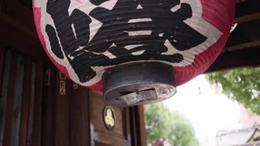 Fukuoka, Japonya-02 Ekim 2025: Japonya 'nın Fukuoka kentindeki Kushida Tapınağı' nın girişinde asılı duran büyük kırmızı fenerlerin ahşap kirişler, ipler ve kutsal süslemelerle çevrili yavaş çekim görüntüsü