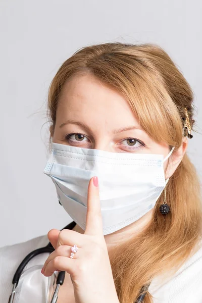 Sjuksköterska med stetoskop och en skyddande mask ber tystnad — Stockfoto