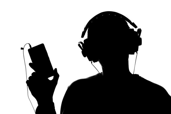 Силуэт молодого человека со смартфоном в наушниках

