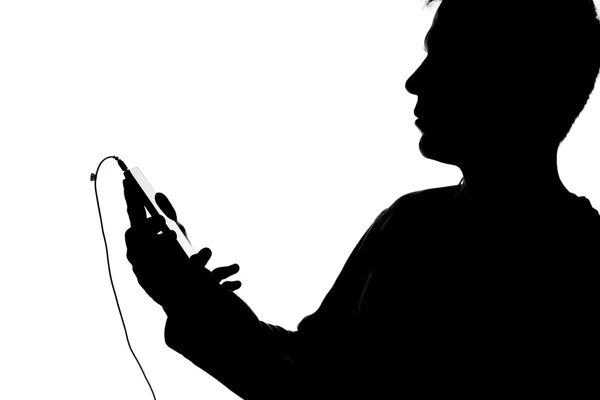 Силуэт молодого человека со смартфоном в наушниках — стоковое фото