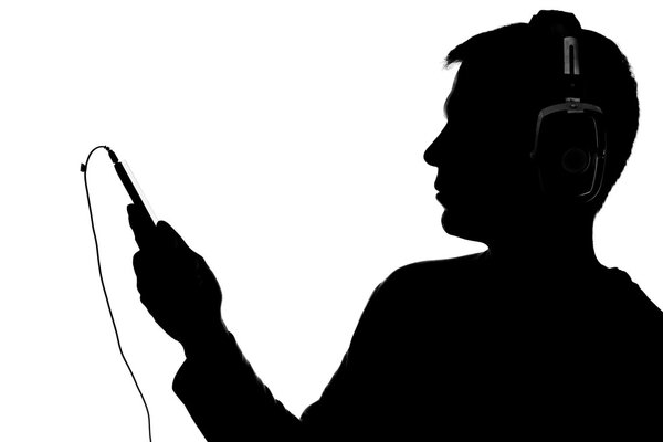 Силуэт молодого человека со смартфоном в наушниках
