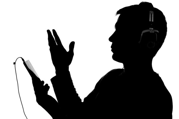 Силуэт молодого человека со смартфоном в наушниках
